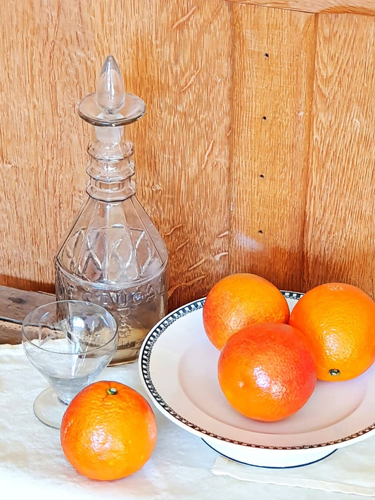picture of dark green vintage cake stand from saint-amand french vintage with blood oranges and a glass