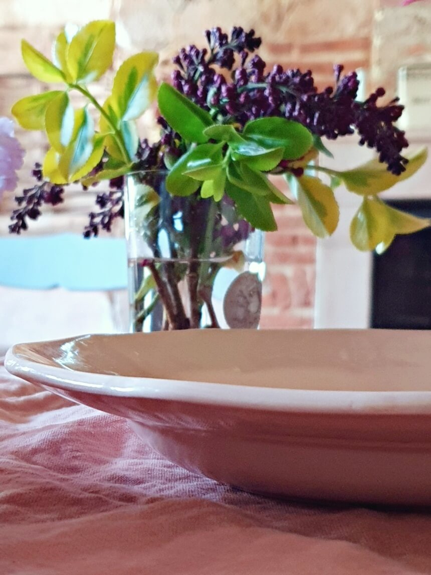 picture of a pink deep plate from digoin sarreguemines on the kitchen table with lilac bouquet