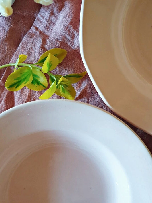picture of two edges of pink deep plates with green leaves middle