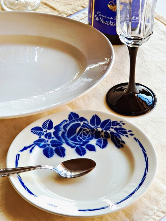 picture of a vivid blue rose vintage dessert plate from Badonviller, France. 'Nicole' series with a black colored wine glass and a red wine.