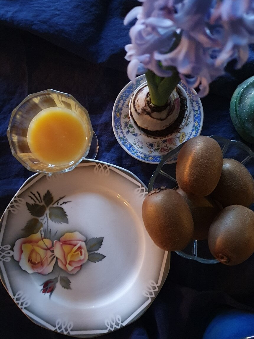 picture of a cup of orange juice with kiwis and a french vintage plate