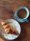 picture of a croissant on a french vintage dessert plate with a coffecup