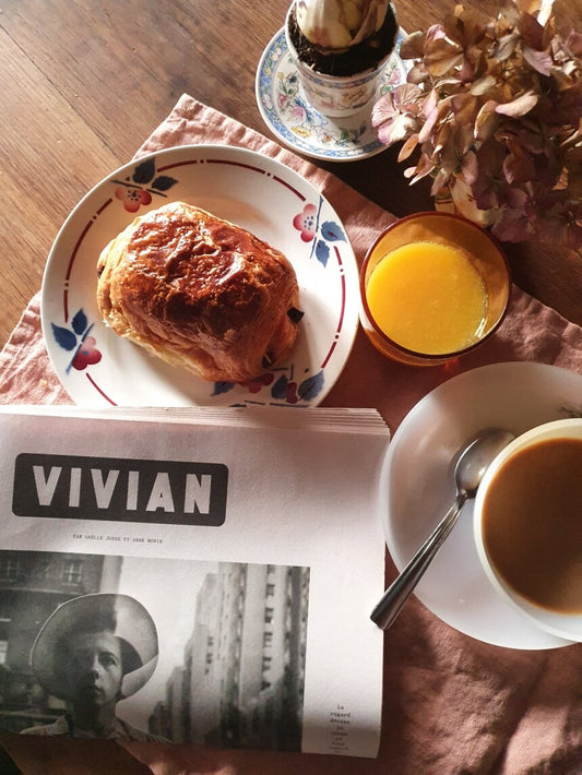 picture of a breakfast with newspaper and orange juice with croissant